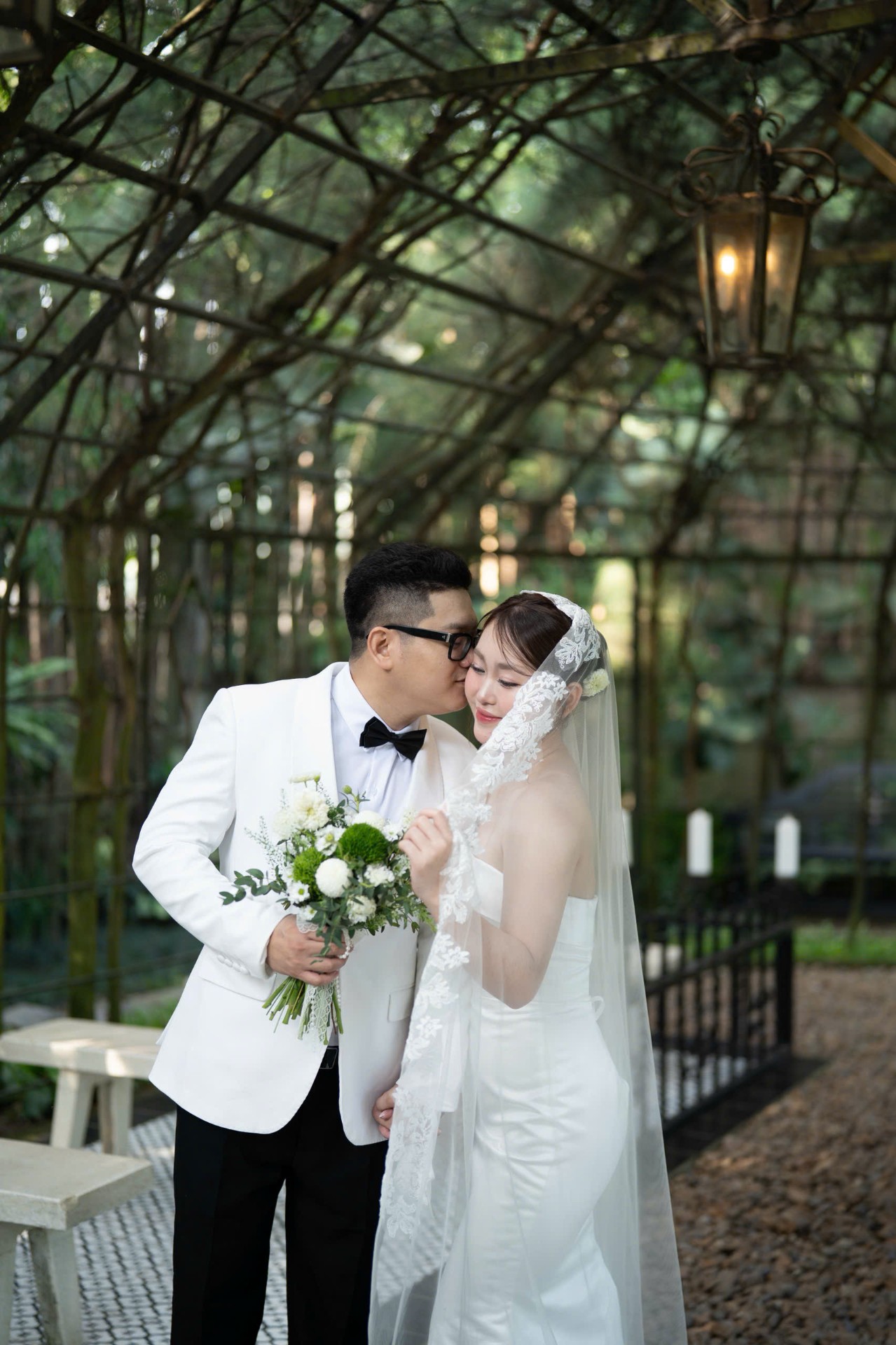 Chú rể hôn nhẹ cô dâu trong nhà kính