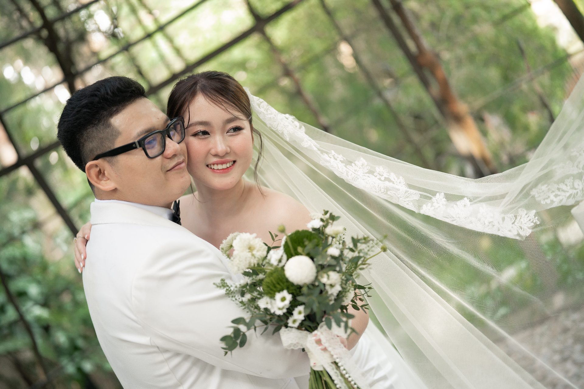 Cô dâu chú rể tựa vào nhau với bó hoa cưới