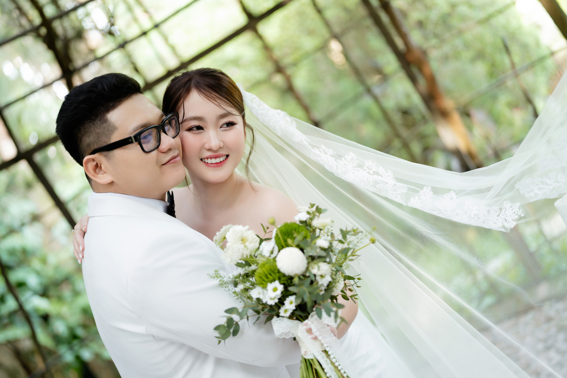 Cô dâu chú rể tựa vào nhau với bó hoa cưới